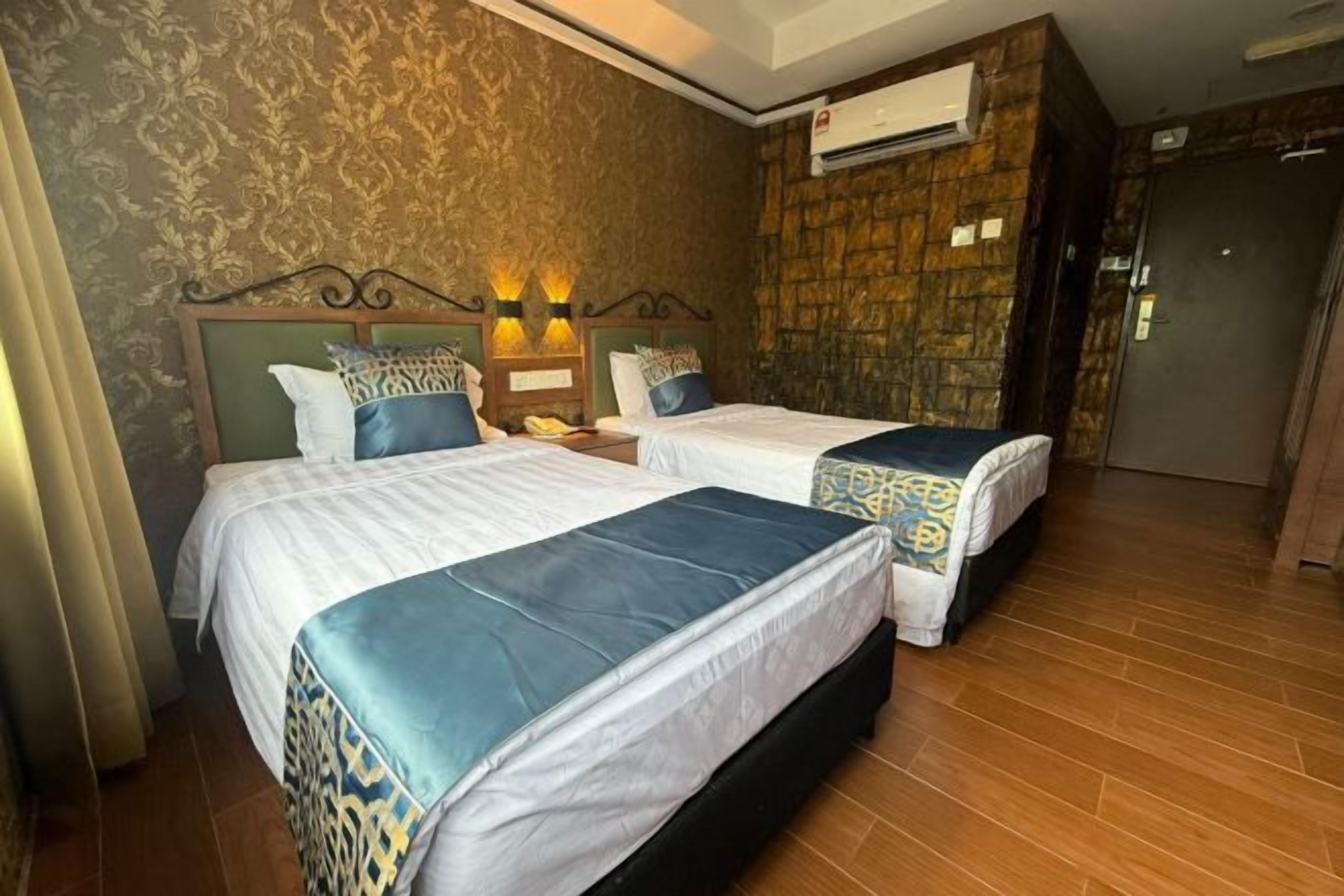 Ein Hotelzimmer mit zwei Betten, einer Wand mit Muster, einer Klimaanlage und einer Holztür.