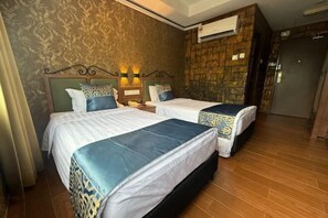 A hotel room with two beds, a patterned wall, an air conditioning unit, and a wooden door. - K Garden Hotel Sungai Petani (Sungai Petani)