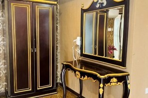 A room with a dark wooden wardrobe, a console table, and a mirror.