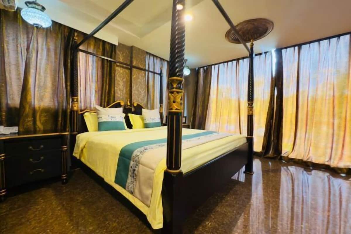 A four-poster bed with a canopy, a nightstand, and a dresser.