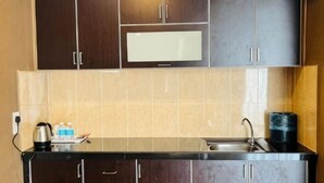 A kitchen with dark cabinets, a microwave, a sink, and a coffee maker. - K Garden Hotel Sungai Petani (Sungai Petani)