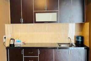 A kitchen with dark cabinets, a microwave, a sink, and a coffee maker. - K Garden Hotel Sungai Petani (Sungai Petani)