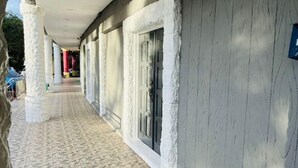 A corridor with white columns and a tiled floor, leading to a building entrance with a door. - K Garden Hotel Sungai Petani (Sungai Petani)