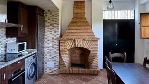 Eine Küche mit Kamin aus Ziegelsteinen, einem Esstisch und einer Waschmaschine.