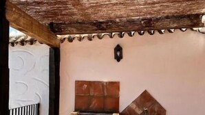 Ein überdachter Patio-Bereich mit Kamin aus Ziegelsteinen und Fliesenboden.