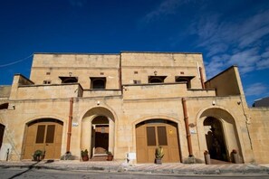 A two-story building with arched doorways and a central entrance. - The Figolla Farmhouse - Gizimina 1 (Ix-Xagħra)