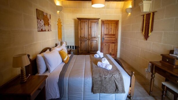 A bedroom with a bed, wooden wardrobe, and a nightstand with a lamp. - The Figolla Farmhouse - Gizimina 1 (Ix-Xagħra)
