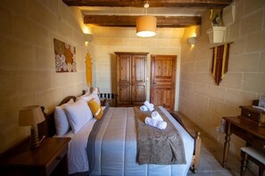 Een slaapkamer met een bed, een houten garderobe en een nachtkastje met een lamp.