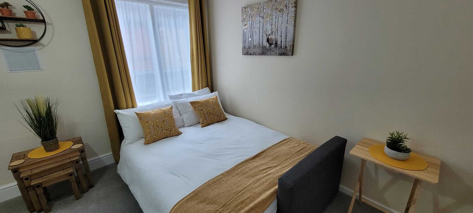 Ein ordentlich eingerichtetes Schlafzimmer mit einem Bett, Nachttischen und einem kleinen Schreibtisch.