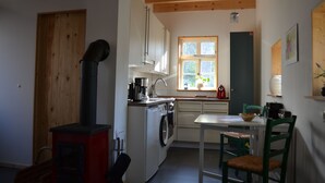 Kompakti keittiö, jossa on liesi, pesukone ja ikkuna, josta on näkymä.