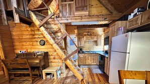 L’intérieur d’un chalet en bois comprend une cuisine, un coin repas et un escalier.