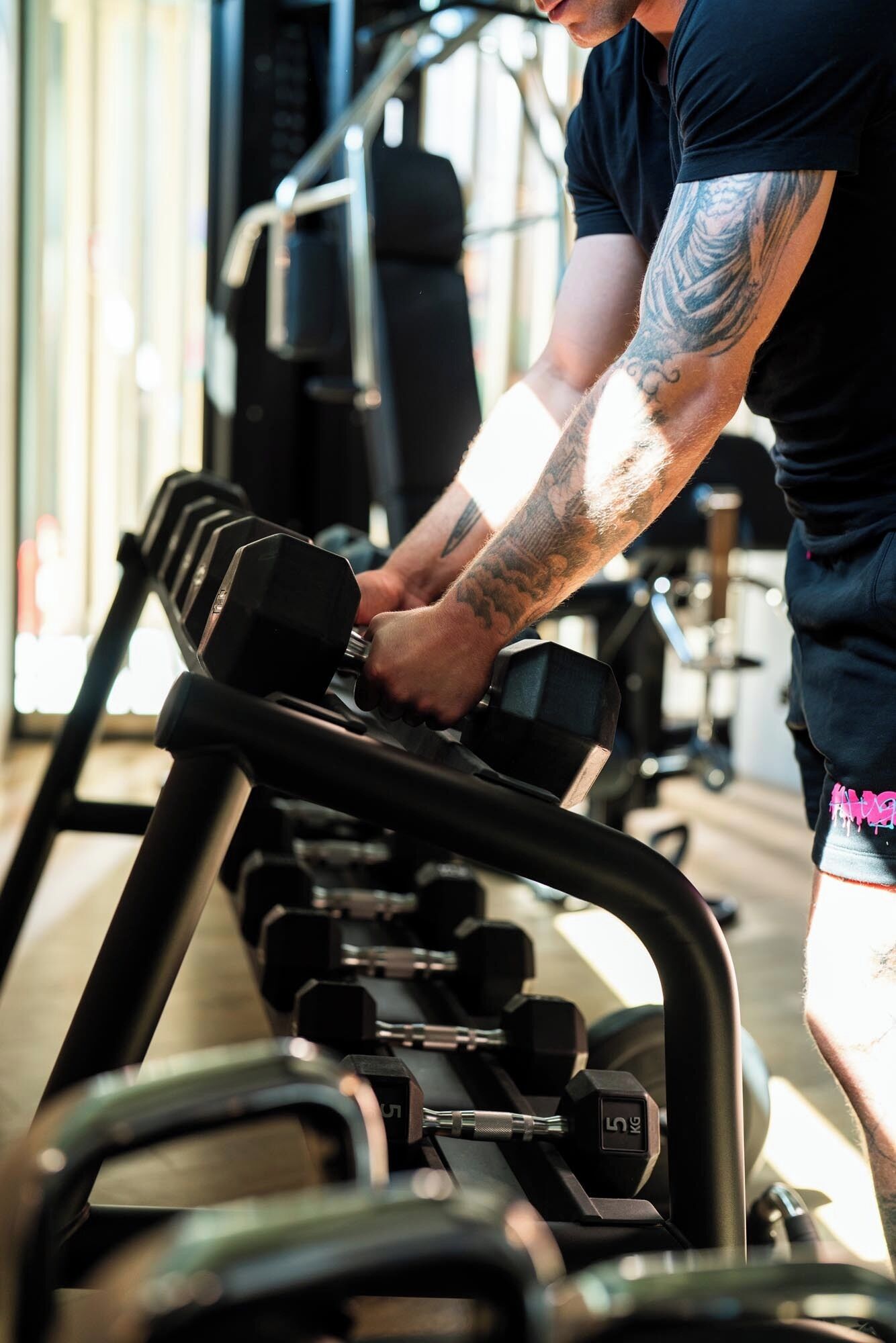Une personne utilise une rangée de haltères réglables dans une salle de sport.