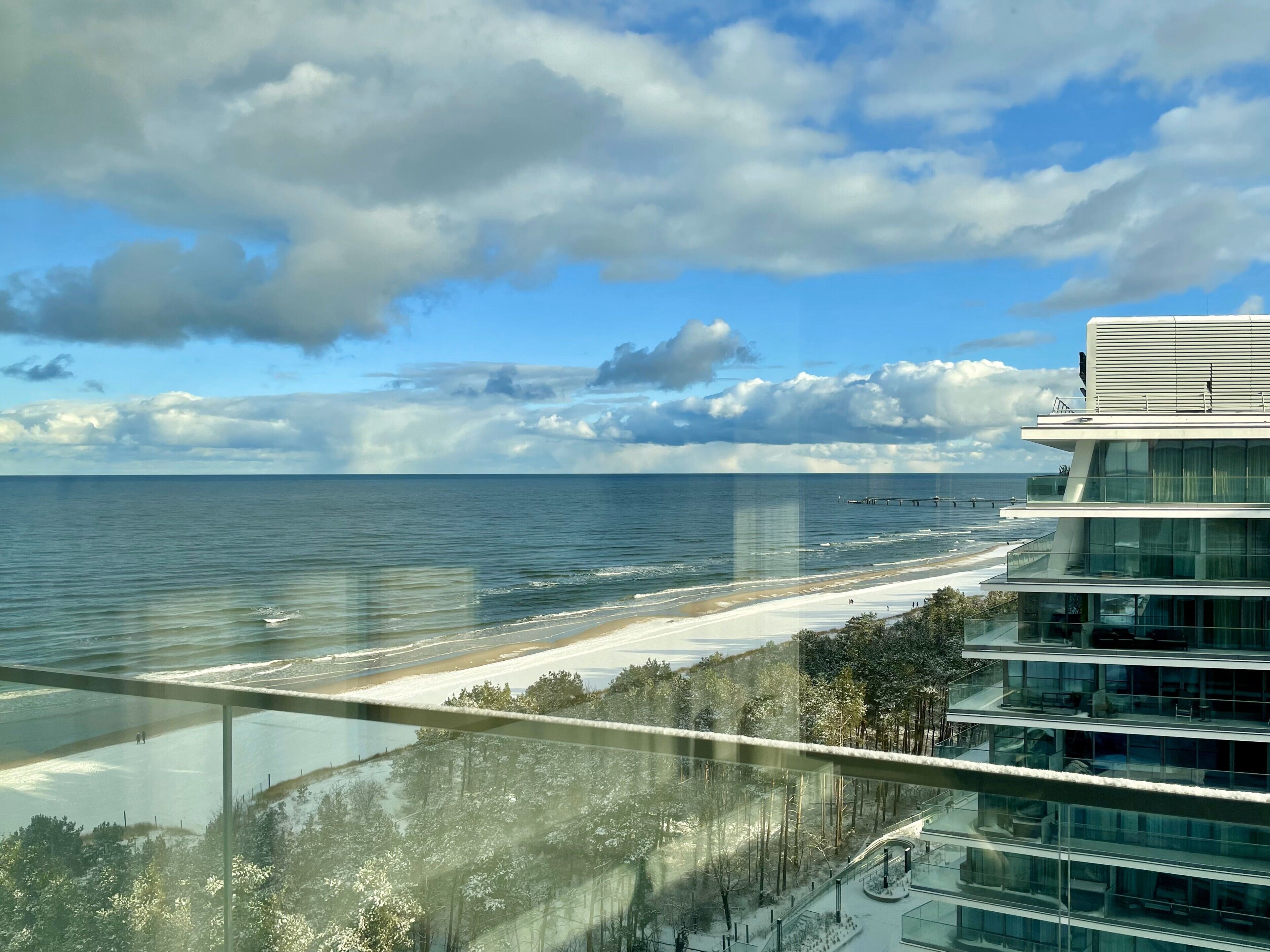 En moderne bygning med en glasfacade, der kigger ud over en strand og et ocean.