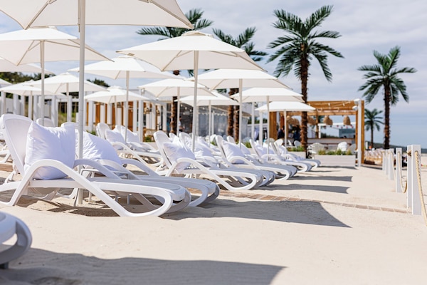 Een privéstrand, wit zand, ligstoelen aan het strand, strandlakens
