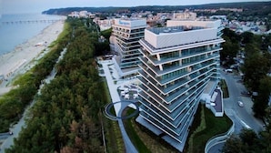 A modern multi-story building with a glass facade, located near a beach and a road. - Wave Międzyzdroje Resort & Spa (Międzyzdroje)