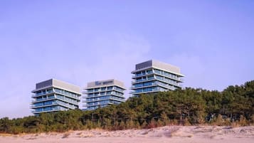 Um hotel moderno com três edifícios interligados, rodeado por uma floresta densa.