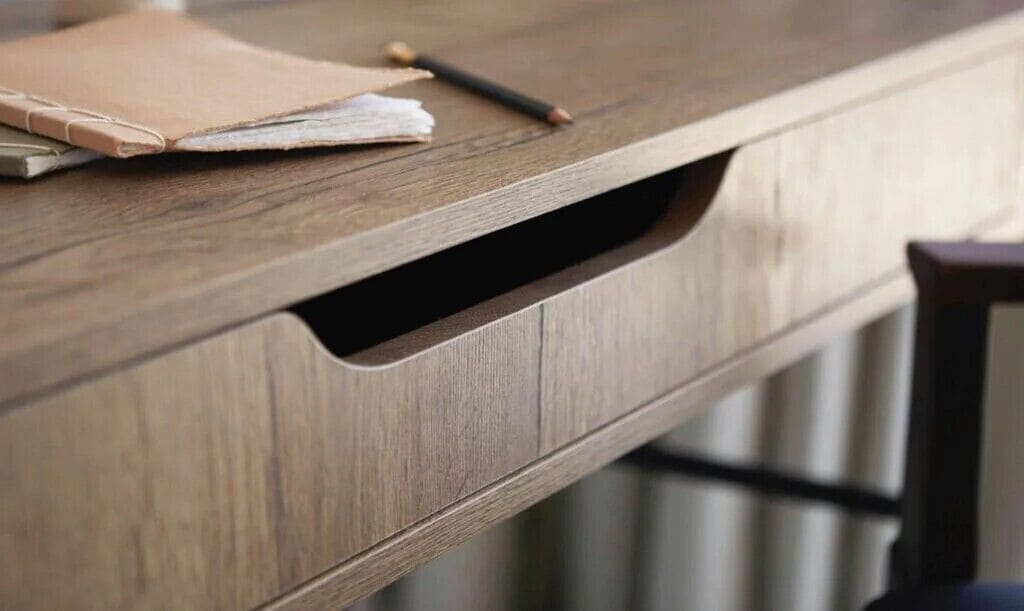 A wooden desk with a drawer and a hole in the front.