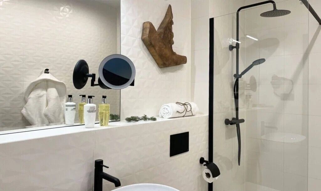 Un baño moderno con cabina de ducha de vidrio, un lavabo blanco y un espejo sobre el lavabo.