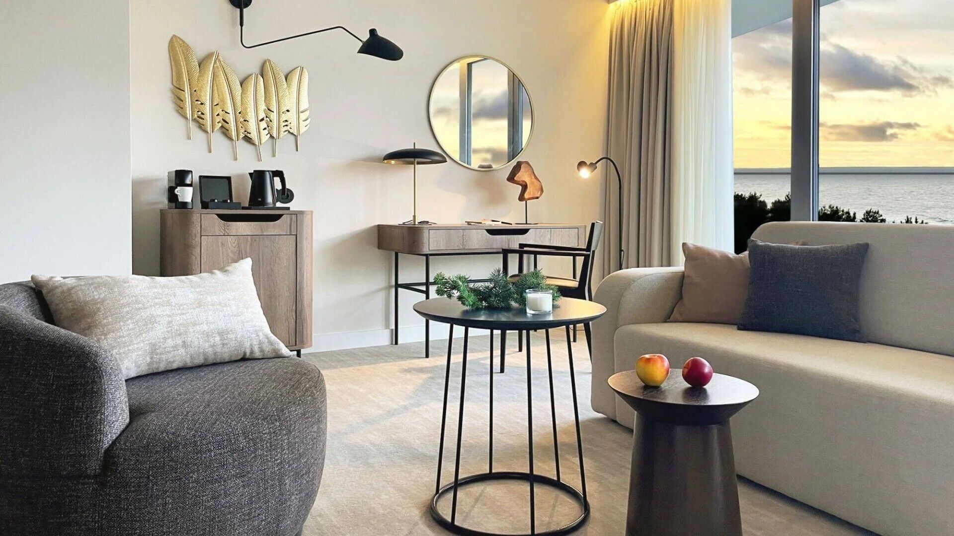 Una sala de estar moderna con sofá, sillón, mesa de centro y vista al mar.
