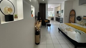Une chambre moderne avec un lit, des tables de chevet, un bureau et une chaise. On peut apercevoir la pièce adjacente.