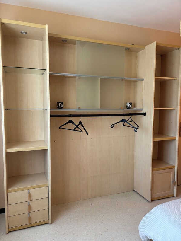 Un placard en bois avec des portes ouvertes, des étagères et une tringle pour suspendre les vêtements.