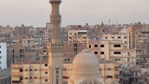 Una mezquita con un minarete alto y una cúpula, rodeada de edificios residenciales muy cercanos.