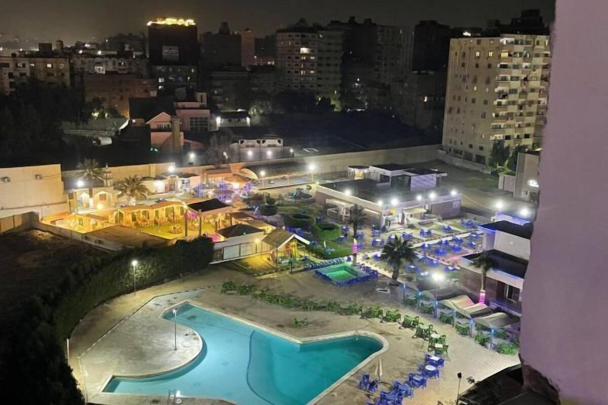 A hotel with a swimming pool, outdoor seating, and a well-lit courtyard.