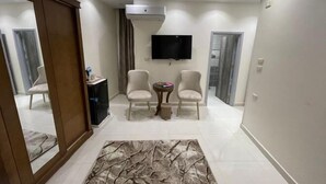 Una sala de estar moderna con un televisor de pantalla plana, dos sillones, una mesita y un tapete estampado.