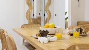 Une table à manger avec un saladier de fruits, un muffin et des verres de jus d’orange.