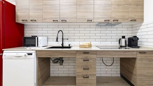 Une cuisine moderne avec des meubles en bois, un crédence carrelée blanche, un lave-vaisselle, un four à micro-ondes, un évier et une machine à café.