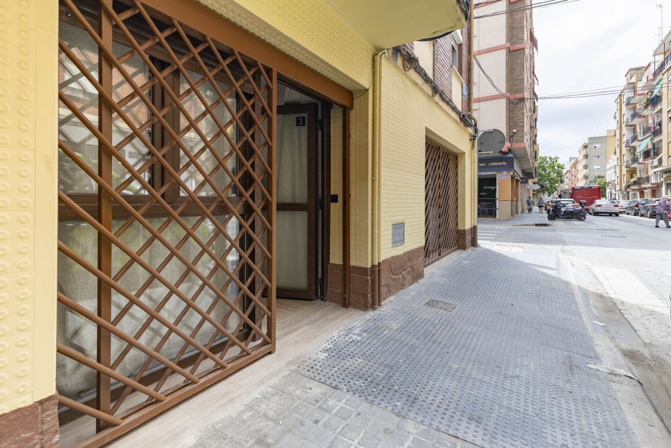 Um edifício com fachada amarela, portão de metal e calçada.