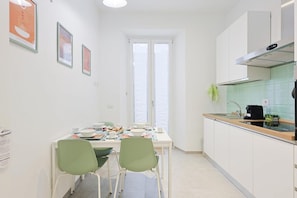 A compact kitchen with a dining table, chairs, and a window.