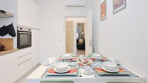 Een moderne keuken met witte kastjes, een inbouwoven en een eethoek met een tafel voor vier personen.
