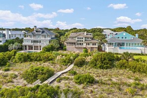 Una zona residencial costera con varias casas, un sendero y abundante vegetación.