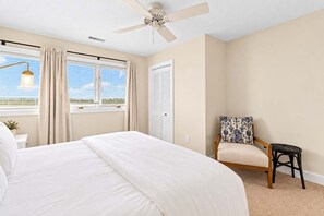 A bedroom with a bed, a chair, a ceiling fan, and a window with curtains. - Oceanfront Home w/ A+ Views & Private Beach Entry! (Isle of Palms)