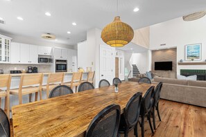 Een moderne keuken met witte kasten, roestvrijstalen apparatuur en een eethoek met een houten tafel en stoelen.