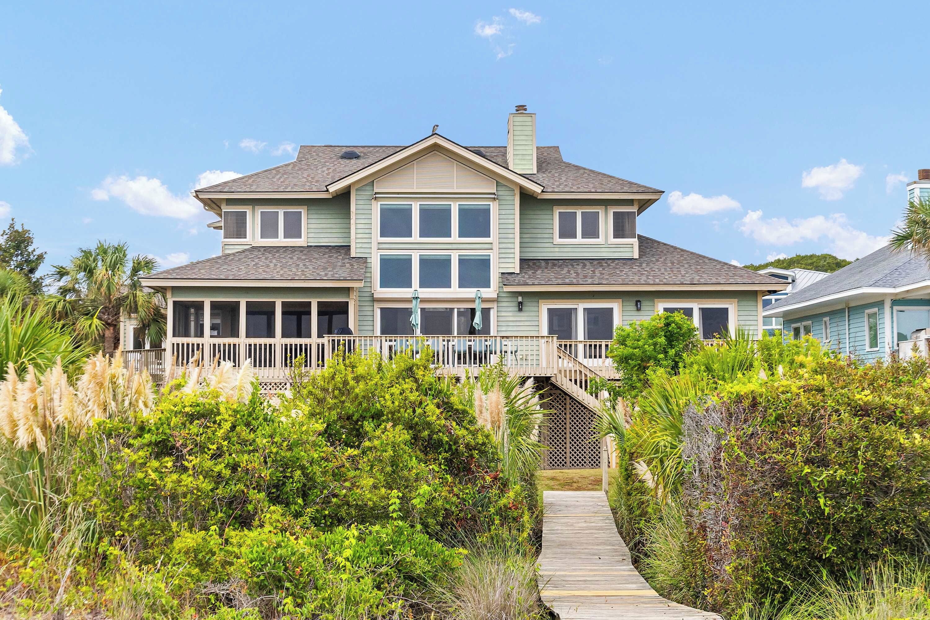 A two-story house with a covered porch and a wooden deck leading to the entrance.
