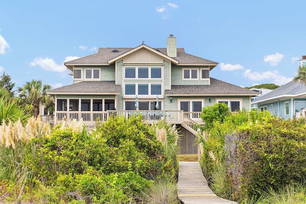A two-story house with a covered porch and a wooden deck leading to the entrance.
