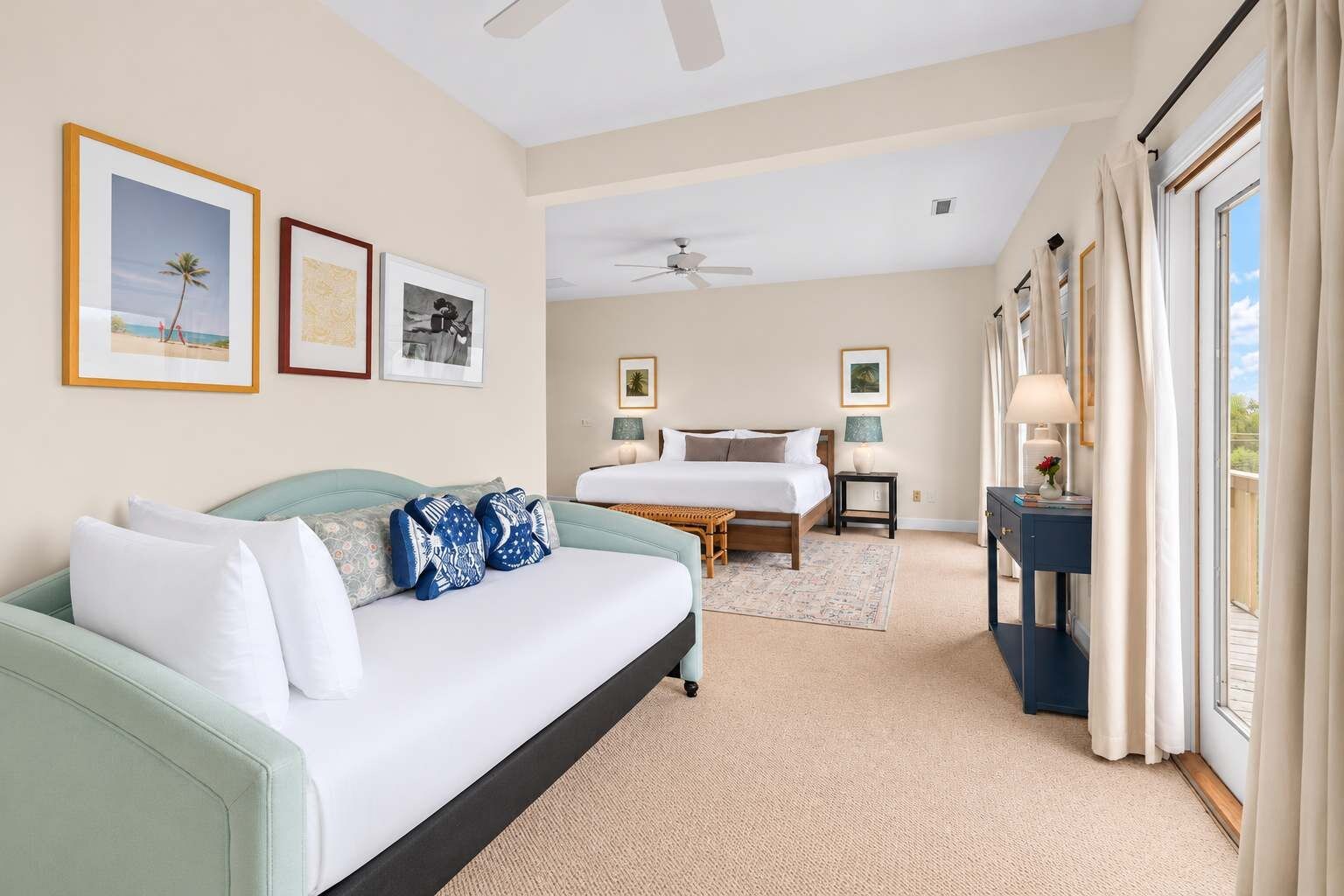 A hotel room with a bed, a sofa, a desk, and a window with curtains.