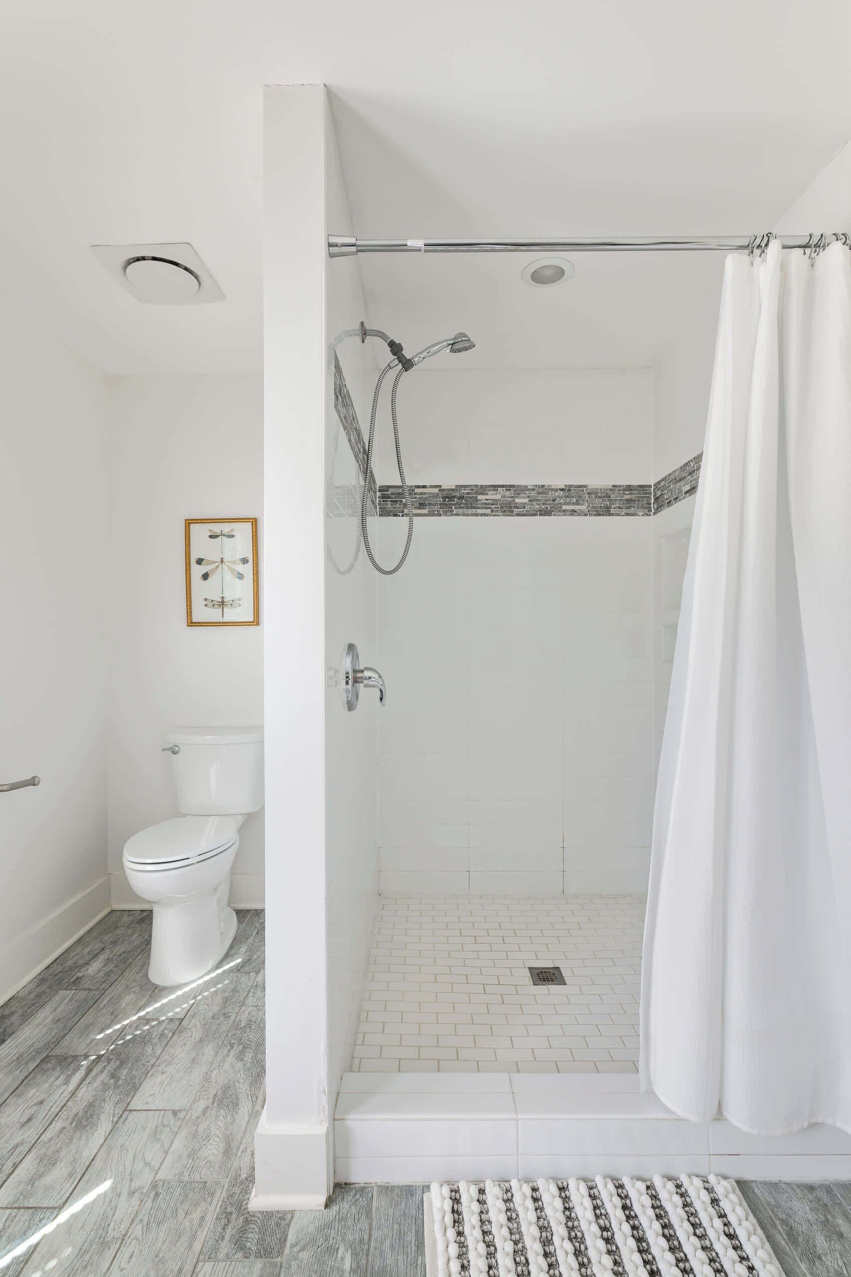 Ein Badezimmer mit Dusche, Toilette und einem gerahmten Bild an der Wand.