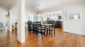 A spacious dining area with a wooden table and chairs, white walls, and a hanging light fixture.