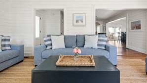 A modern living room with a grey sofa, a black coffee table, and a woven tray with a vase of flowers.
