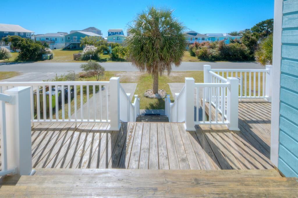 A wooden deck leading to a gated entrance with a palm tree in the center.