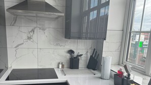 Eine moderne Küche mit Spüle aus Edelstahl, schwarzen Schränken, einem Gasherd und einem Fenster mit Blick auf Gebäude.