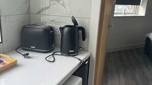 Eine kompakte Küche mit Waschmaschine, Toaster und Wasserkocher auf der Arbeitsfläche.
