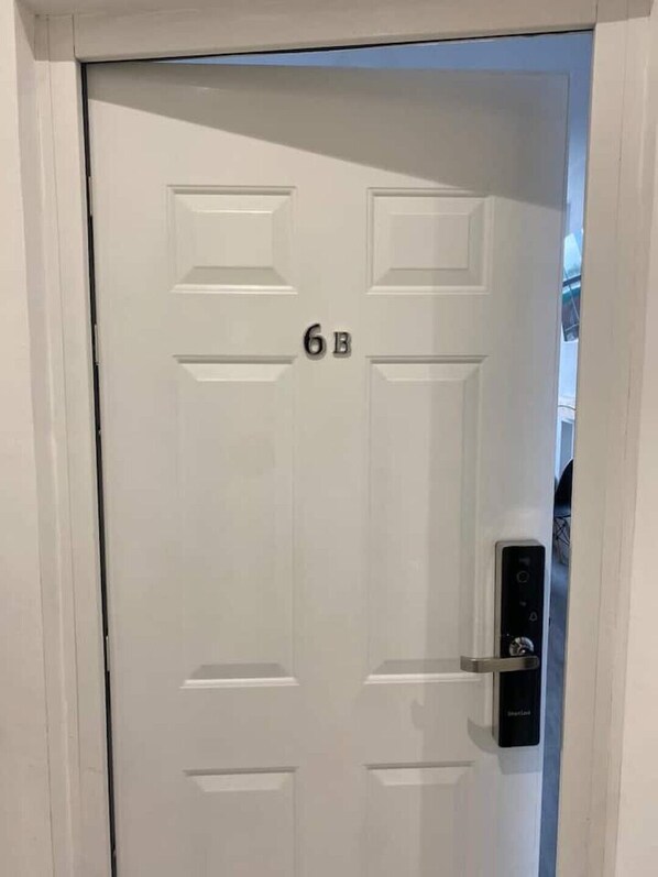 A white door with the number 6B, a keypad lock, and a small window.