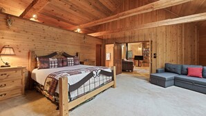 A wooden-paneled bedroom with a bed, a dresser, a sofa, and a bookshelf. - Poplar 35 - Fun 3 Level Home, Pool Table, A/C, Hot Tub (Sunriver)