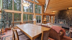 A spacious wooden interior with a large dining table, leather sofa, and a stone fireplace. - Poplar 35 - Fun 3 Level Home, Pool Table, A/C, Hot Tub (Sunriver)