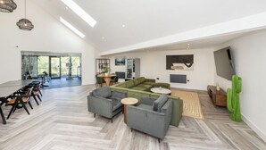 A spacious living area with a large sofa set, a dining table with chairs, and a television mounted on the wall. - Riverside House by UTDM (Salford)