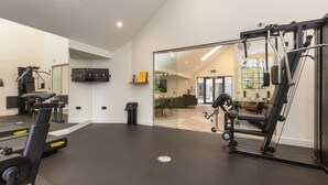 A gym with cardio machines, weightlifting equipment, and a large mirror. - Riverside House by UTDM (Salford)